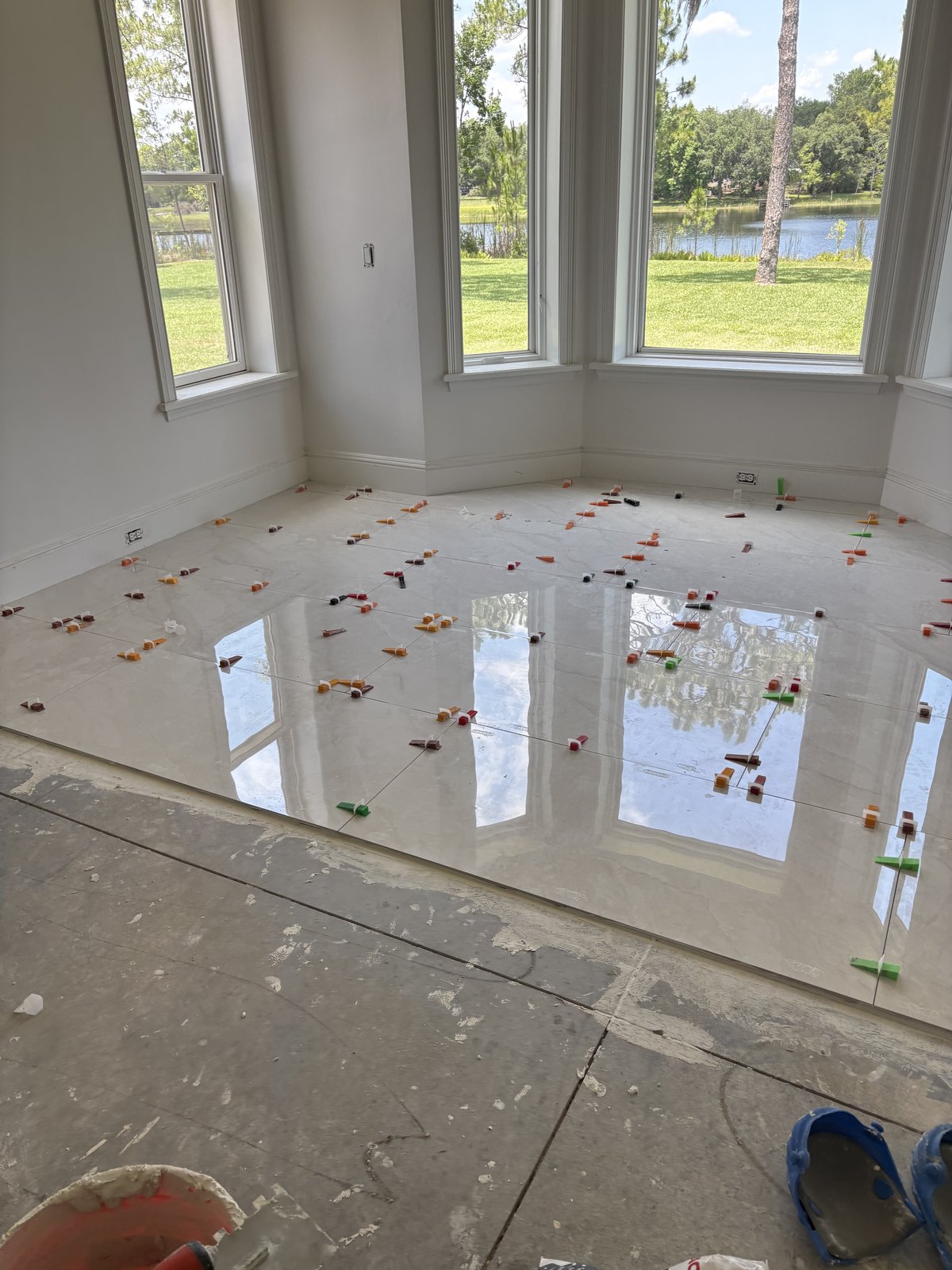 Nivelación de precisión de porcelanato pulido de gran formato en una sala luminosa frente al lago.