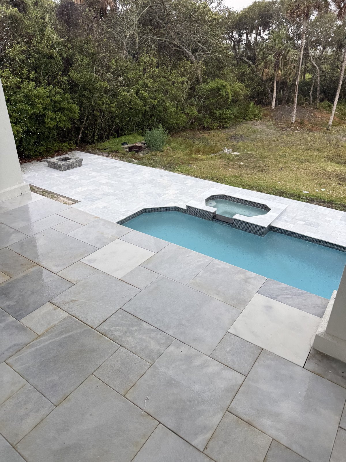 Mejora de espacios exteriores: terraza de piscina con adoquines de mármol y borde de spa, hecha para lucir bajo el sol de Florida.