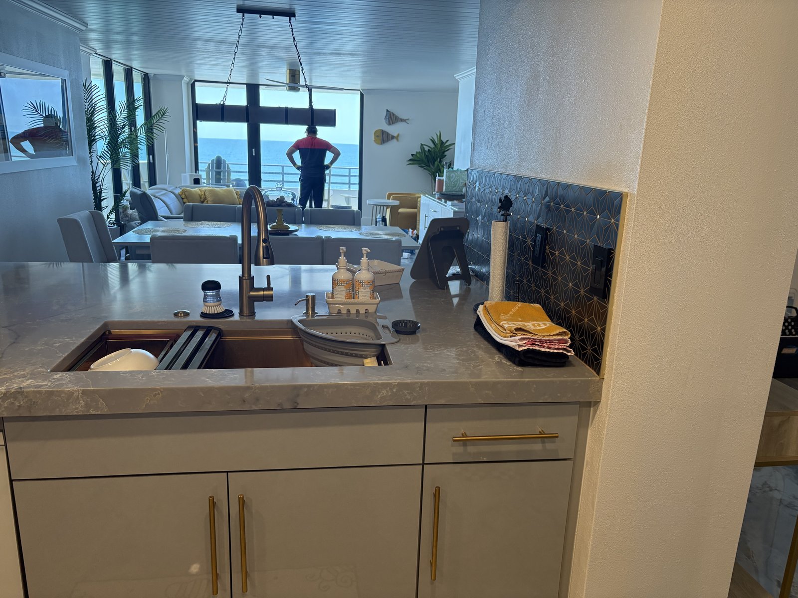 Remodelación de cocina en condominio frente al mar con encimeras de cuarzo, fregadero tipo estación de trabajo en tono cobre y grifería de latón.