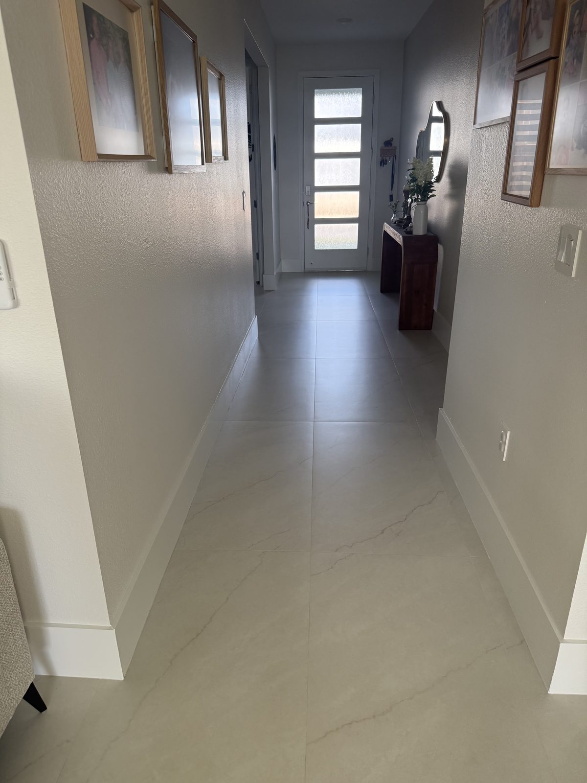 Elegante porcelanato de gran formato con apariencia de mármol que aporta un acabado luminoso y continuo a este acogedor pasillo de entrada.