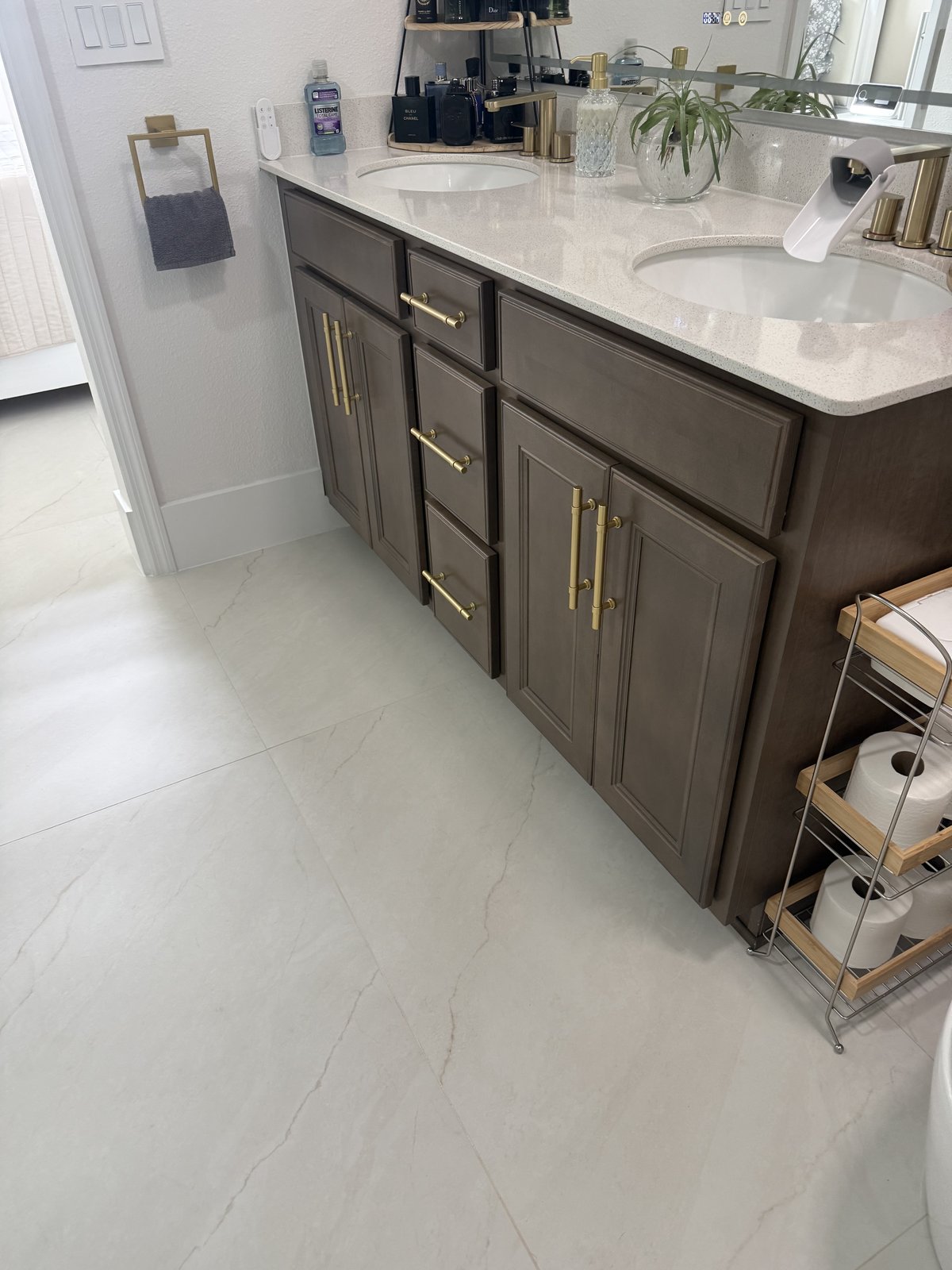 Tocador doble renovado, combinado con nuevo piso de porcelanato de gran formato y herrajes dorados cálidos.