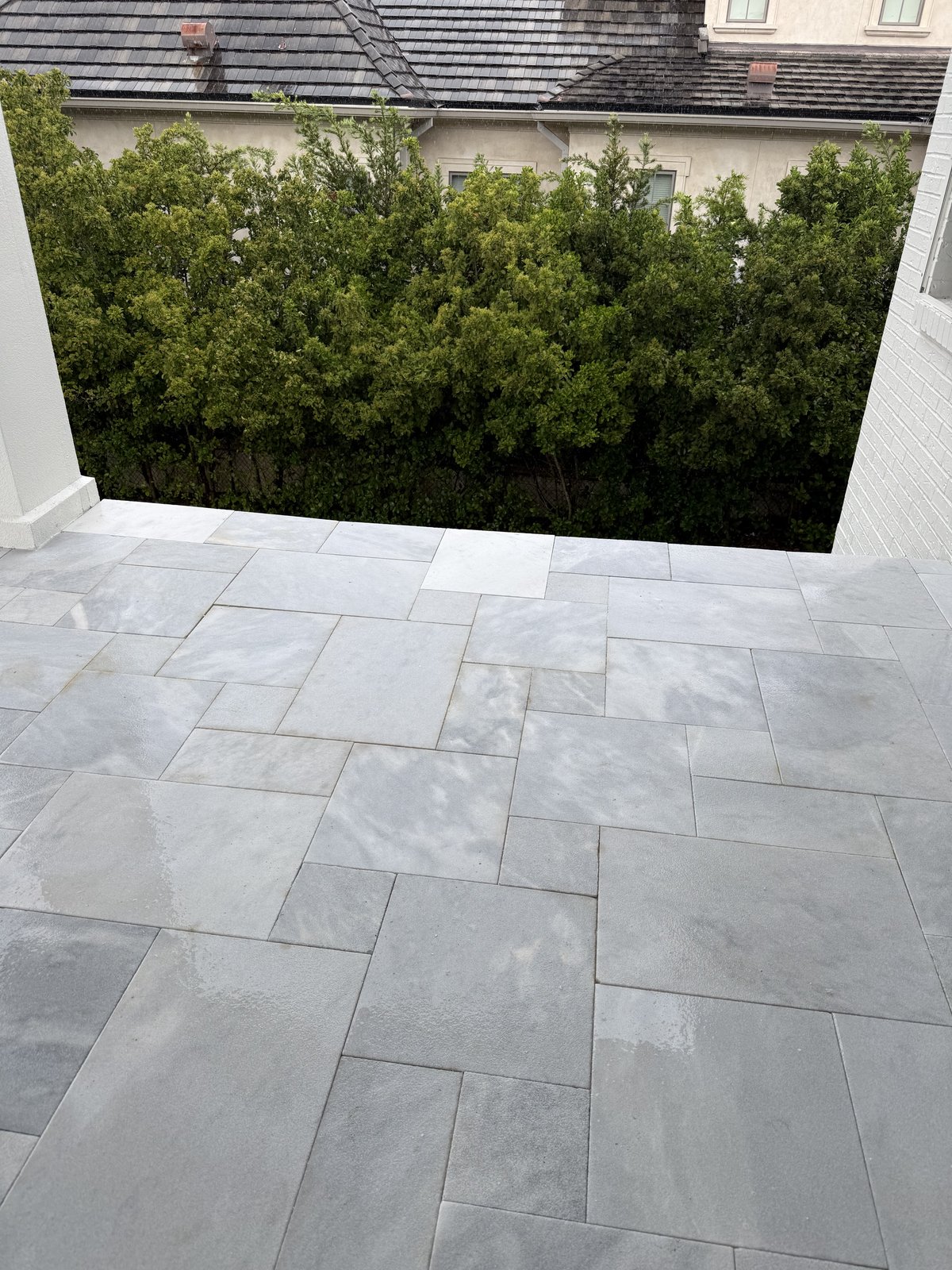 Elegante patio exterior terminado con adoquines de piedra natural de gran formato, colocados en un patrón ashlar impecable y hecho para resistir el clima de Florida.