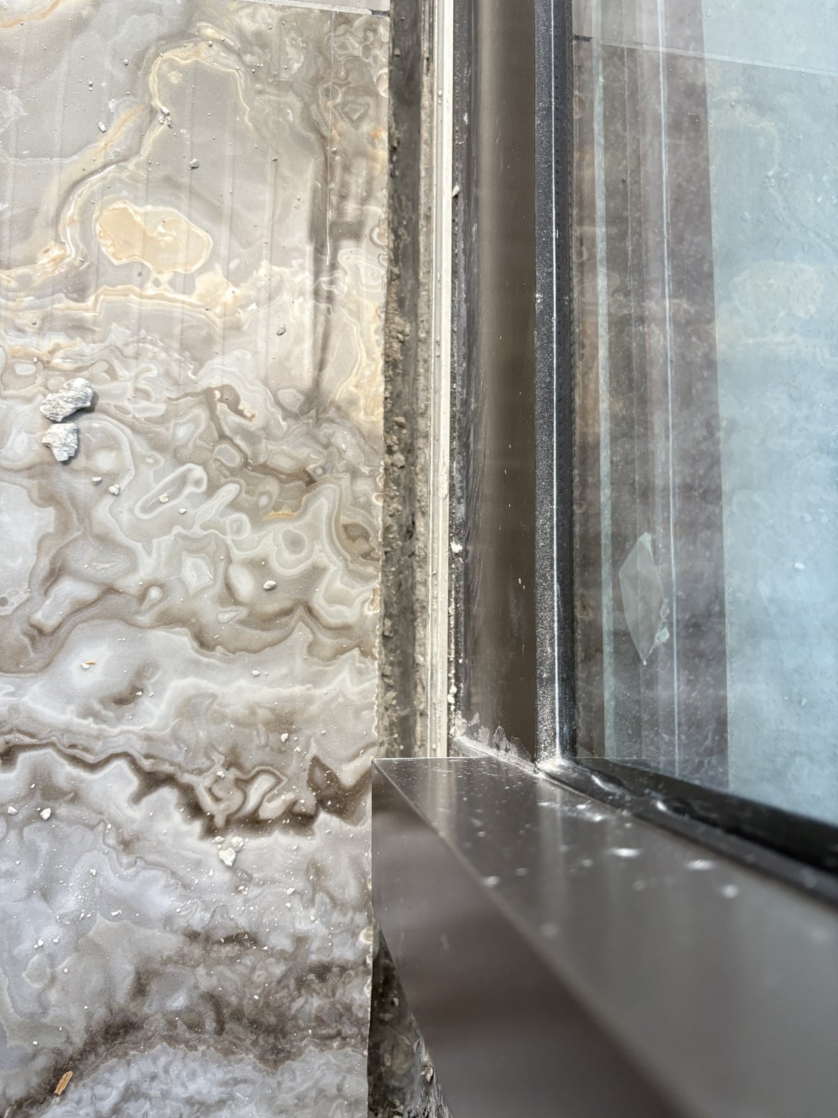 Detalle de porcelanato tipo ónix instalado con ajuste perfecto contra el marco de una ventana.