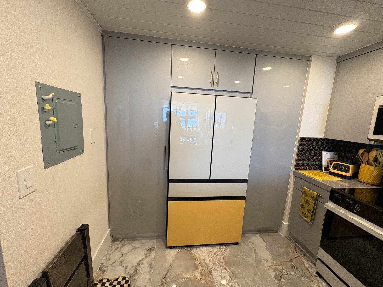 Cocina moderna de condominio con gabinetes de alto brillo, paneles de refrigerador de diseñador y pisos de porcelanato tipo mármol.